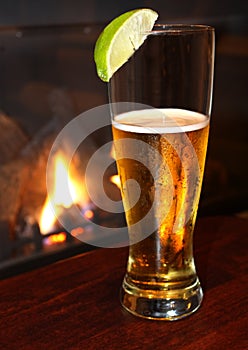 Refreshing beer with lime, fireplace background