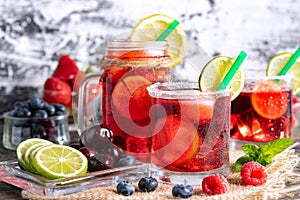 Refreshing berry cocktail with ice and lemon. Raspberry, lime, strawberry, blueberry, and leaves mint. Berry mojito close-up