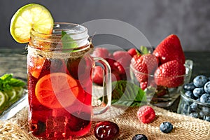 Refreshing berry cocktail with ice and lemon. Raspberry, lime, strawberry, blueberry, and leaves mint. Berry mojito close-up