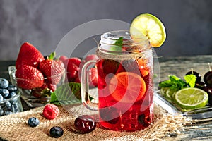 Refreshing berry cocktail with ice and lemon. Raspberry, lime, strawberry, blueberry, and leaves mint. Berry mojito close-up