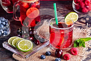 Refreshing berry cocktail with ice and lemon. Raspberry, lime, strawberry, blueberry, and leaves mint. Berry mojito close-up