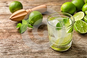 Refreshing beverage with mint and lime in glass on wooden table