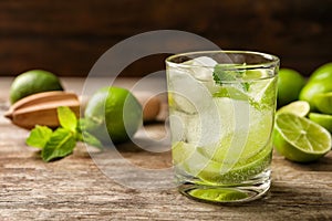 Refreshing beverage with mint and lime in glass on table