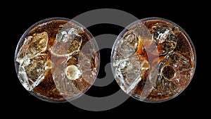 Refreshing bubbly soda pop, set of two top view cold cola glasses isolated on black background with clipping path.