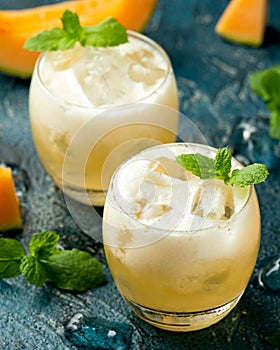 Refreshing Cantaloupe Melon cocktail with ice and mint on rustic table