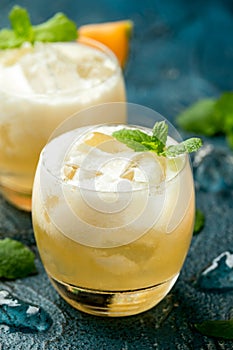 Refreshing Cantaloupe Melon cocktail with ice and mint on rustic table