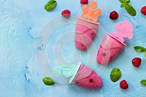 Refreshing children`s ice cream popsicles rasberry sorbet on blue concrete background. Copy space, top view flat lay background