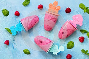 Refreshing children`s ice cream popsicles rasberry sorbet on blue concrete background. Top view flat lay background