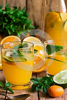 Refreshing citrus lemonade from lime oranges fresh mint in glasses and bottle, sliced scattered fruits