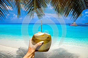 Refreshing coconut cocktail in woman and man hand. Coconut water drink on the Maldives beach.