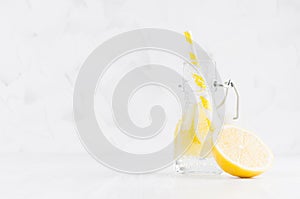 Refreshing cold fruit drink with citrus lemon, bright bubbles and straw in transparent yoke bottle in elegant white interior.