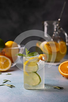 Refreshing cold summer drink with orange, lemon, lime, mint and rosemary. A misted glass with ice and citrus slices.