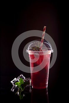 Refreshing cool lemonade with strawberries, mint and ice in plastic glass