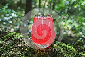 Refreshing cool summer lemonade from strawberry, raspberries, grapefruit or red currants. Pink cocktail drink in glass outdors on