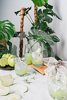 Refreshing delicious of iced guava juice in a glass and sliced guava placed on white marble, houseplant green plant background.