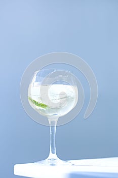 refreshing drink in glass with ice on sunlight and blue background. Ice cubes crystal clear water