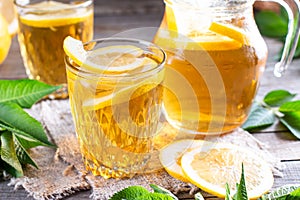 Refreshing drink, iced tea with lime wedges in glass on a wooden table. Summer drinks