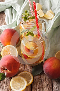 Refreshing drink with lemon, peach, ice and mint in a glass jar.