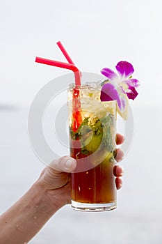 Refreshing drink with lime, mint and pineapple on a tropical beach, close up. Mojito cocktail