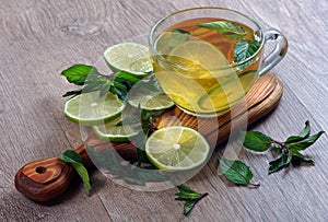 Refreshing drink with mint and lime. a cup of mint tea with lime on a wooden table.