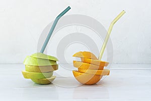 Refreshing drink from whole apple and orange with glass straws.