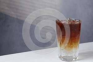 Refreshing espresso tonic drink on white wooden table, space for text