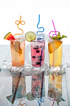 Refreshing flavoured spritzers garnished with fruit and surrounded by ice.