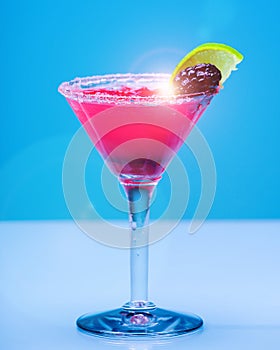 Refreshing fruit cocktail on pastel blue background, with sunflare