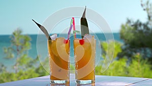 Refreshing fruit drinks with ice cubes falling into glasses