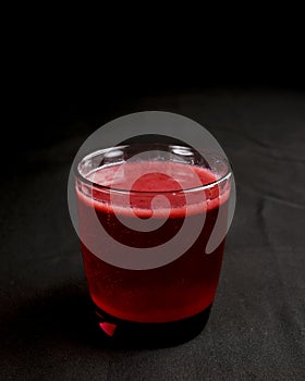 Refreshing fruit punch beverage in glass over black background. Isolated on black