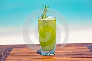 Refreshing garden delight cocktail on wooden table with ocean background at the beach