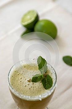 Refreshing glass of beverage with green lime on the table for garnish