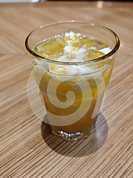 Refreshing A Glass of Coconut and Orange Fusion Drink on Wooden Table