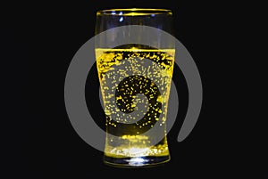 Refreshing glass with light in nadir saturating the interior of the glass and the soda with black background creates a dramatic