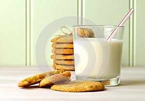 Refreshing glass of milk with a drinking straw, and delicious snack of homemade peanut butter cookies. With a tied stck of cookies
