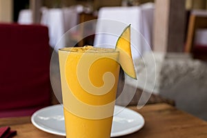 Refreshing glass of tropical mango juice on a wooden table. Bali island, Indonesia.