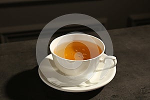 Refreshing green tea in cup on dark textured table, closeup