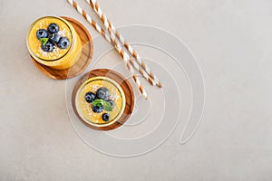 Refreshing and healthy mango smoothie with coconut flakes and fresh blueberries