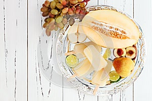 Refreshing ice pops over silver tray. Pear, peach, grape, lime, honeydew white sangria paletas - popsicles. Top view photo