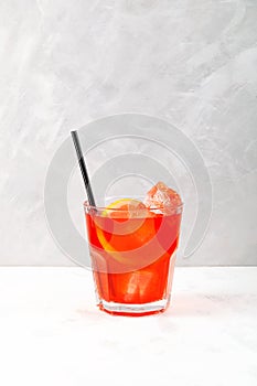 Refreshing iced drink. Glass of Red cold cocktail with ice cubes and drinking straw