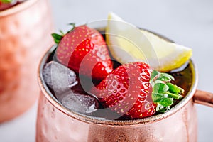 Refreshing iced Moscow mule alcoholic cocktail in copper mugs with strawberry and lemon