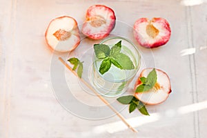 Refreshing iced tea with peppermint and peaches on grey background, selective focus. water drink with peaches