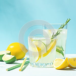 A refreshing lemon lime drink with ice cubes in glass goblets against a blue background. Summer cocktail. Copy space.