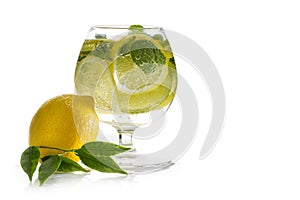 Refreshing lemon water. A glass with fresh slices of lemon and lime with mint leaves in cold water with ice and air bubbles. Clean