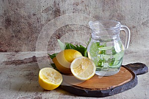 Refreshing lemonade in a beautiful decanter, lemons, fragrant sprigs of mint on the table.