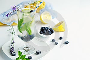 Refreshing lemonade with blueberries and basil on white bsckground