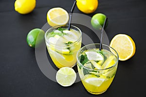 Refreshing lemonade in glass with limes, lemons