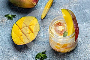 Refreshing mango ice cream with mint leaves and fresh mango served in a glass jar. Food recipe background. Close up