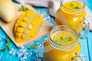 Refreshing mango smoothies in glass with ripe mano