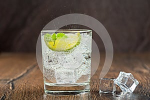 Refreshing mineral water in a glass with ice cubes, mint leaves and lime slice.